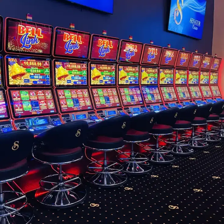 A bank of Bell Link jackpot machines at Casino Senator La Joya, each with a black stool carrying the Senator S monogram