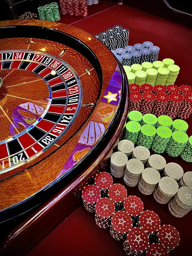 The roulette wheel at Casino Senator La Joya, with green, red, blue and grey chips racked in stacks on the red baize beside it