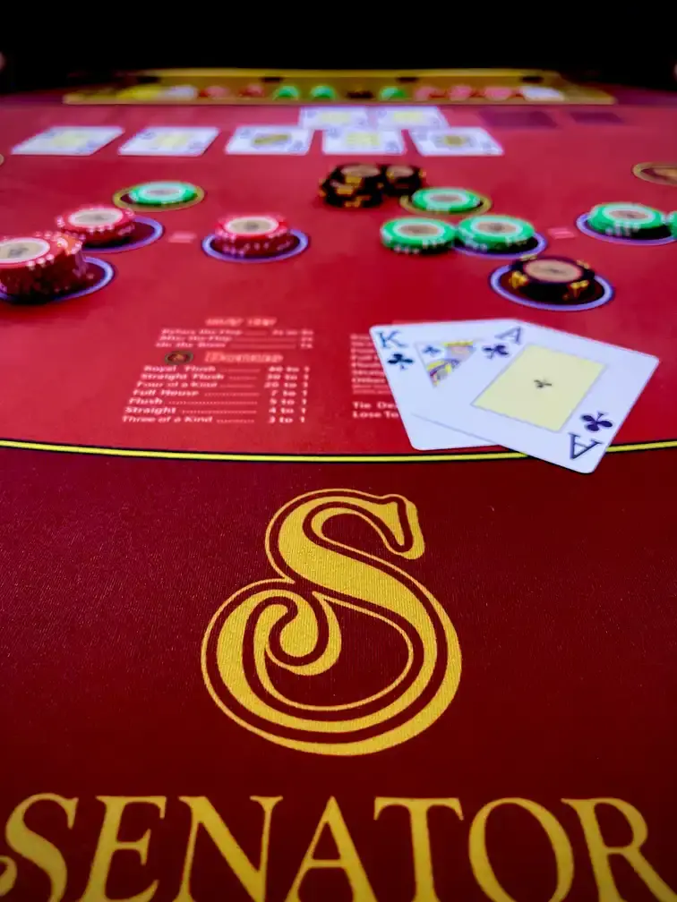 A live card table at Casino Senator La Joya, a king and an ace face up on red felt beside stacked chips, the gold Senator S printed on the layout