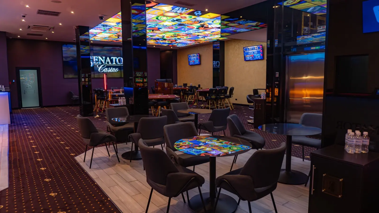 The lounge at Casino Senator La Joya, low tables and armchairs under a backlit ceiling panel, the Casino Senator sign on the wall behind