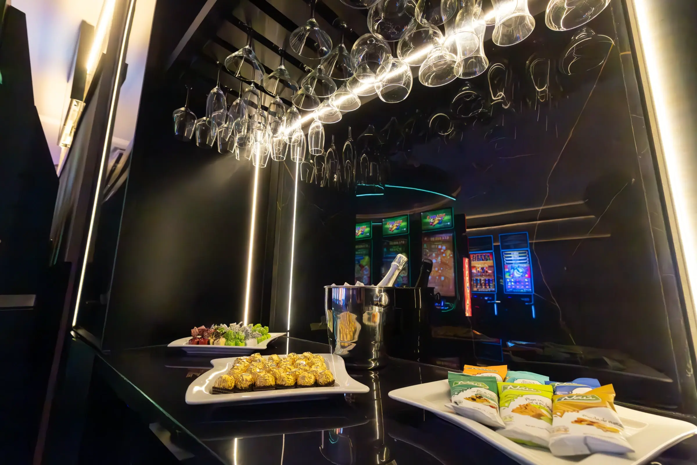 Glassware hanging over the bar counter, with the lit gaming floor behind it, Guatemala