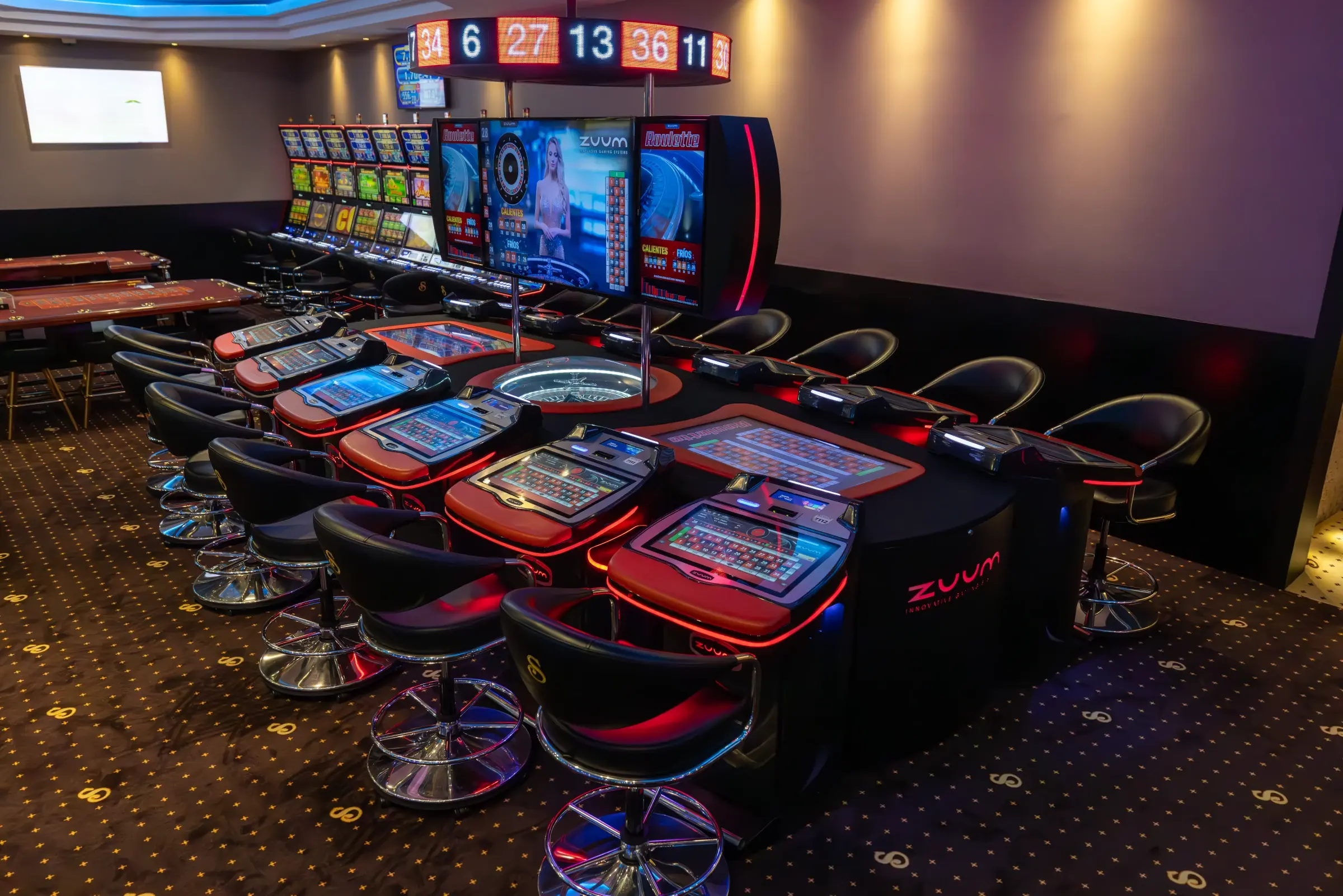 A bank of electronic roulette terminals facing a live dealer screen, with the last winning numbers lit on the board above, Guatemala