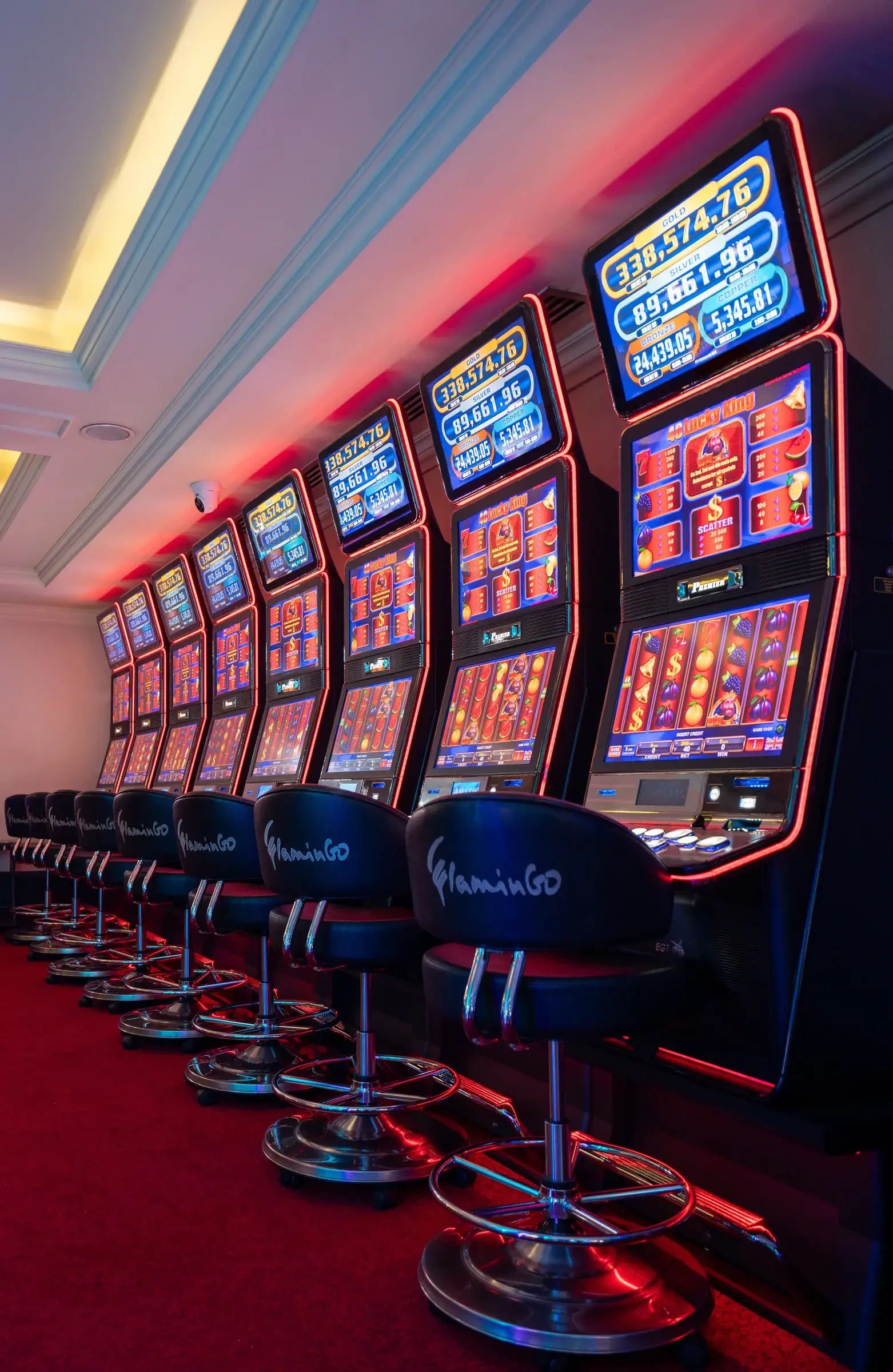 A row of slot machines at Casino Flamingo, each screen under its own jackpot board