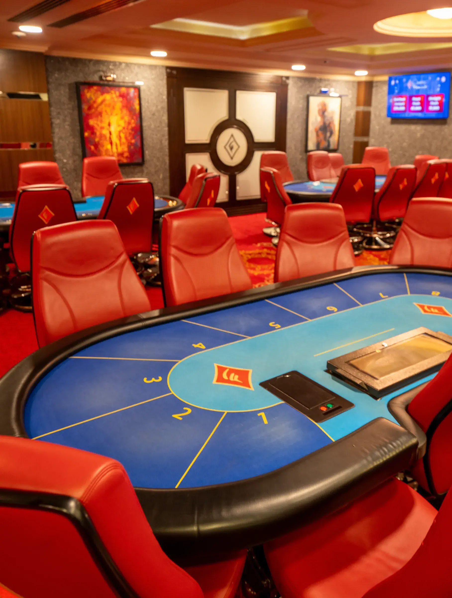 Blue felt card tables with red leather chairs in the Flamingo poker room, framed paintings on the walls