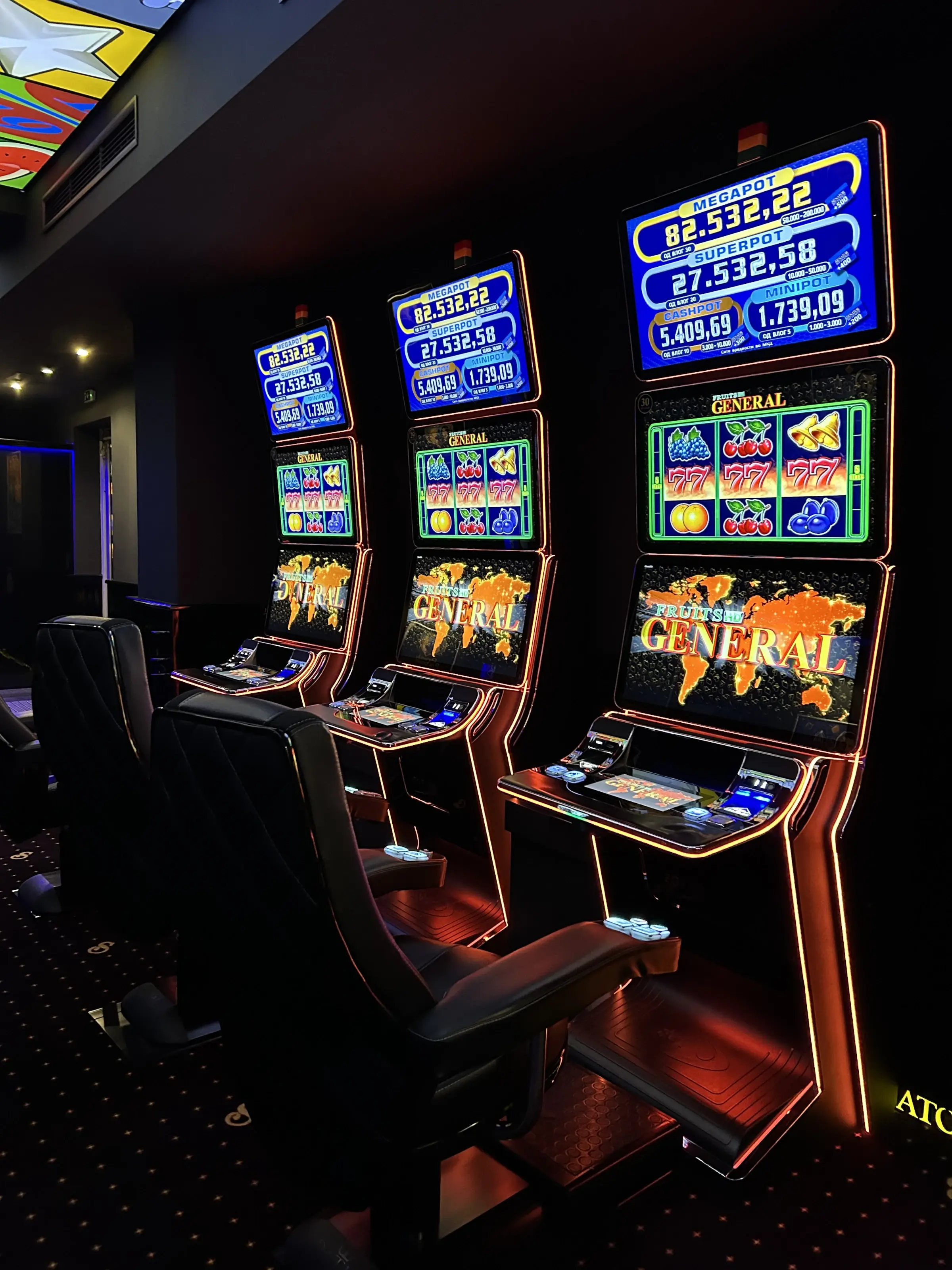 Three slot cabinets with linked jackpot totals lit on the screens above them