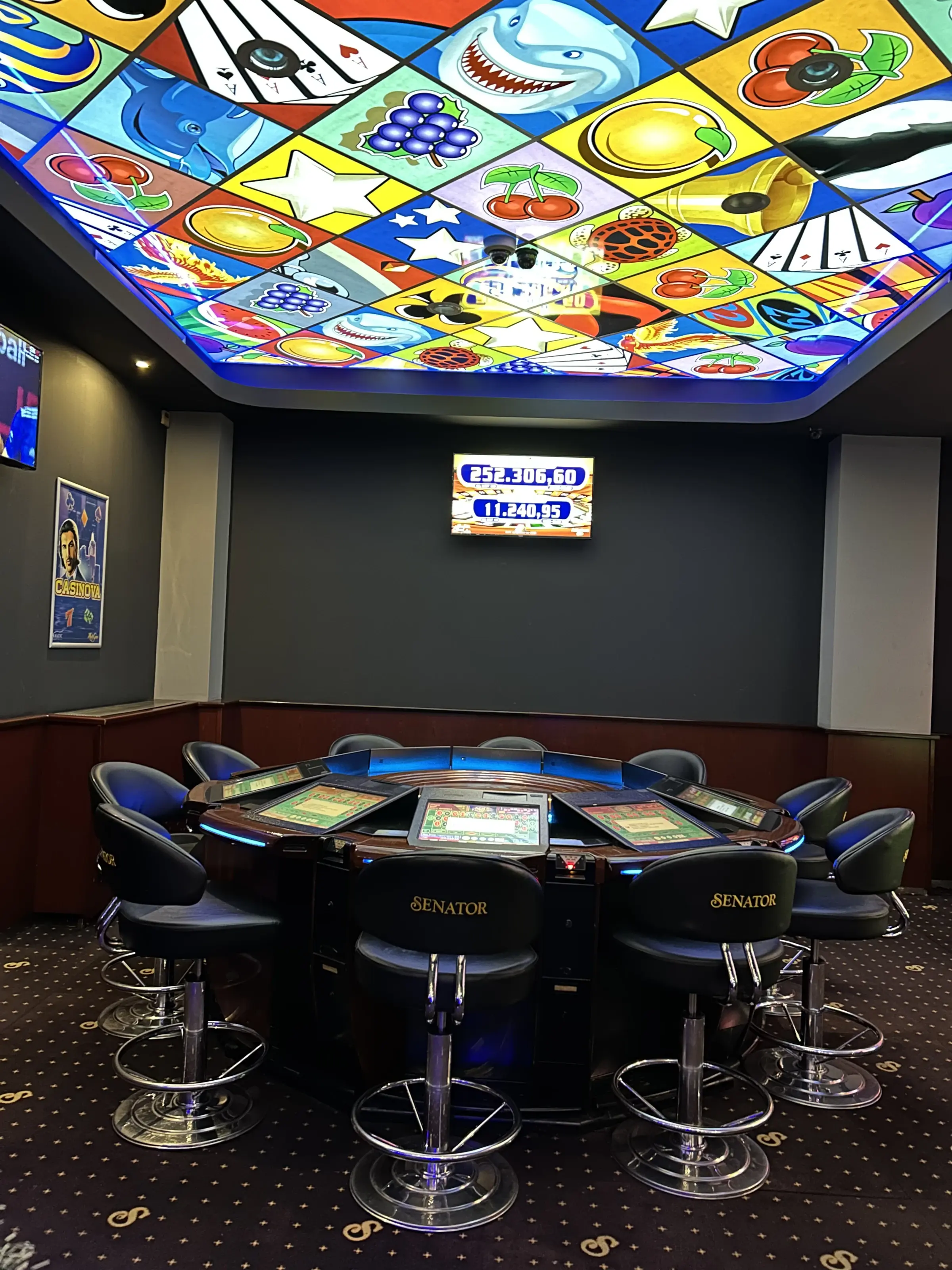 An electronic roulette table with Senator chairs under a full stained glass ceiling, a jackpot screen on the wall