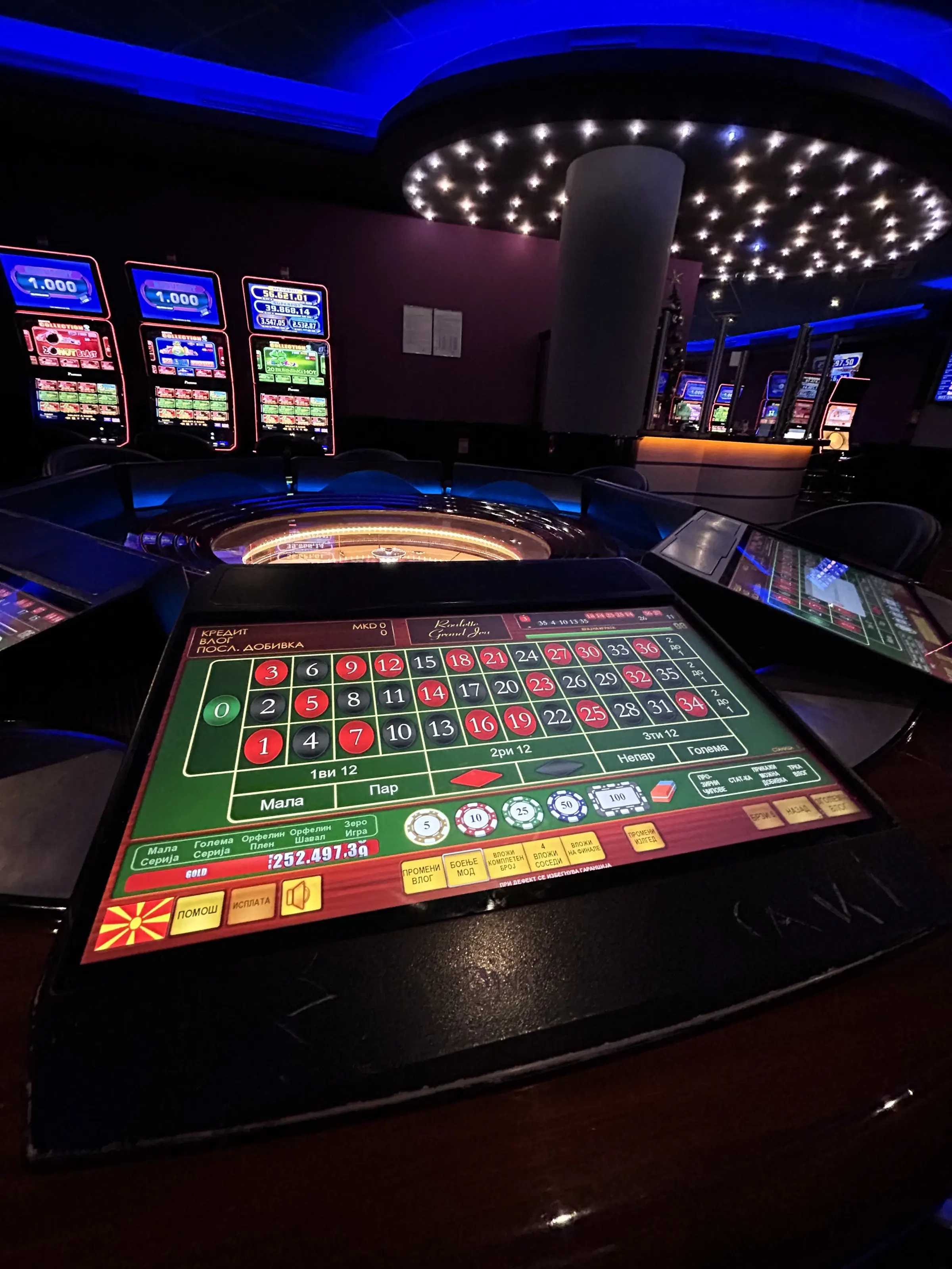 An electronic roulette terminal in close up, its betting grid labelled in Macedonian, the wheel and a ring of lights behind it
