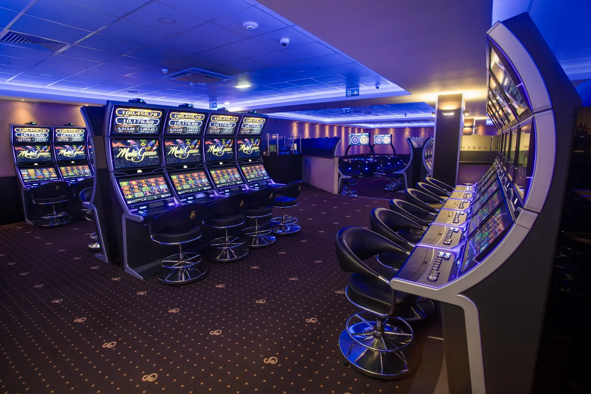 Two banks of slot machines facing each other under blue cove lighting, Senator Club, Mauritius