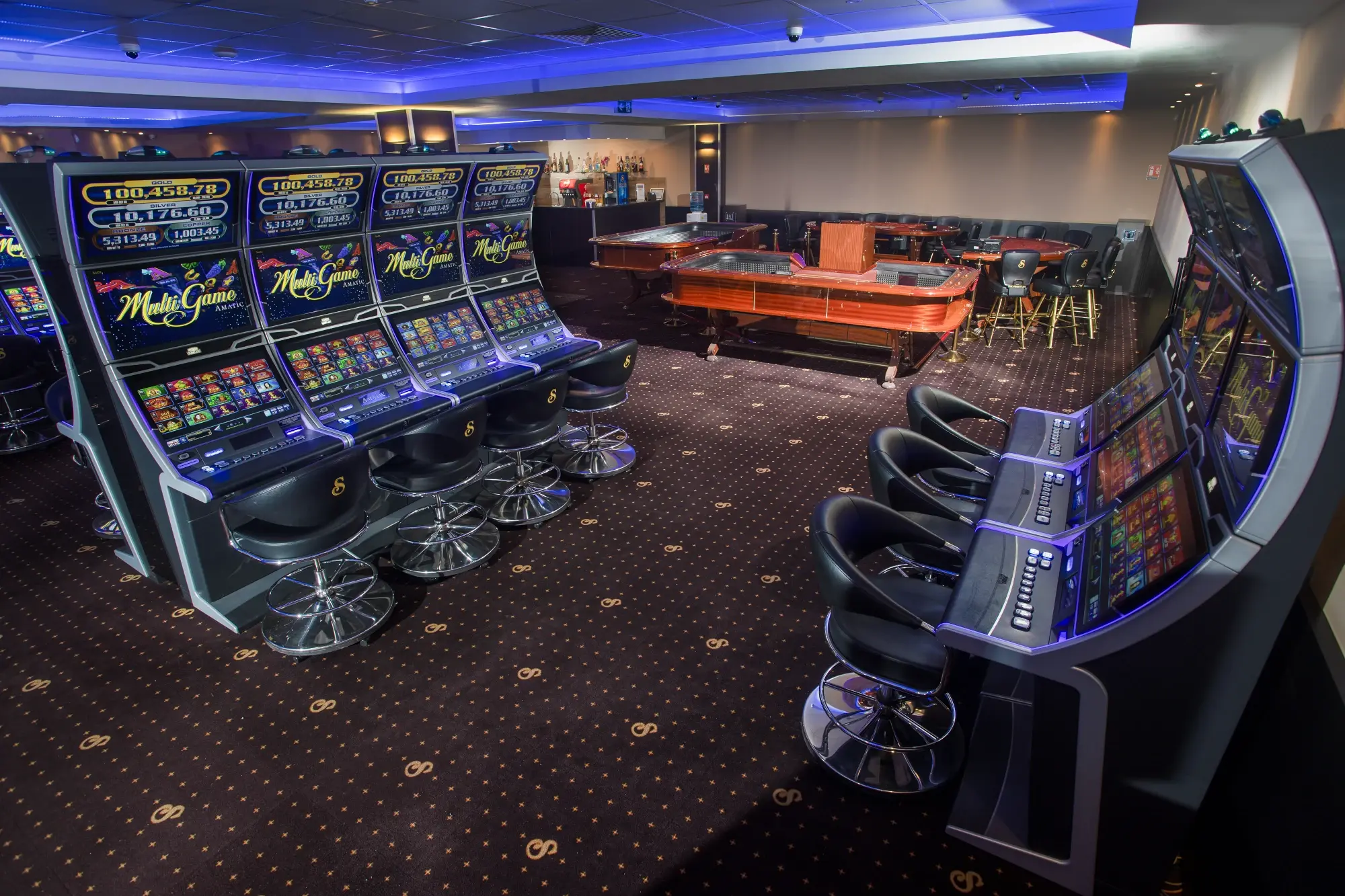 Slot machine banks on both sides of the room with a mahogany gaming table and the bar beyond, Senator Club, Mauritius