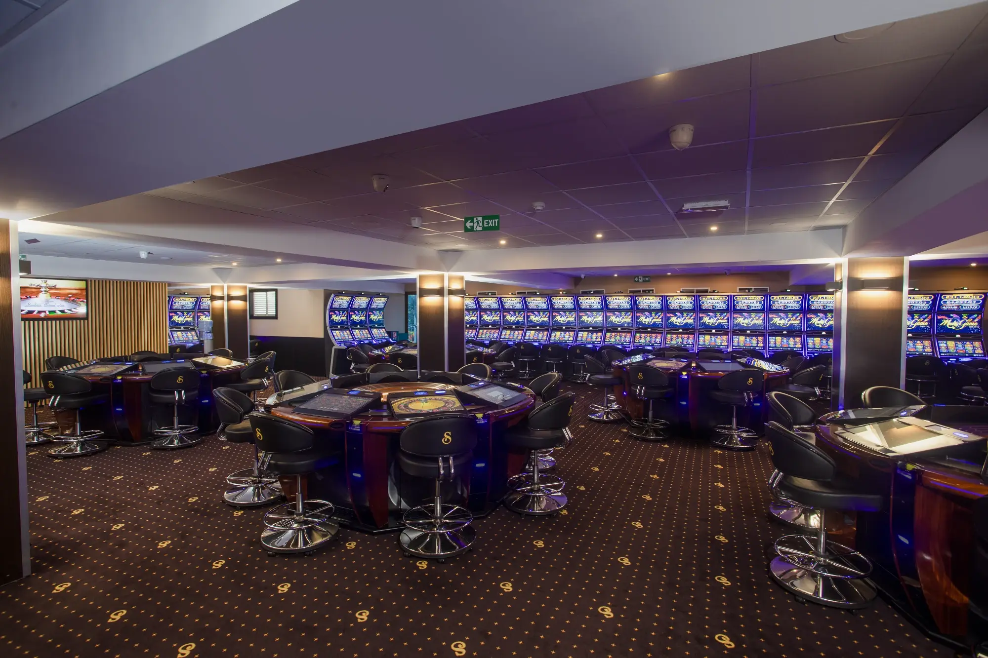 The gaming floor seen across a roulette table towards a long wall of slot machines, Senator Club, Mauritius