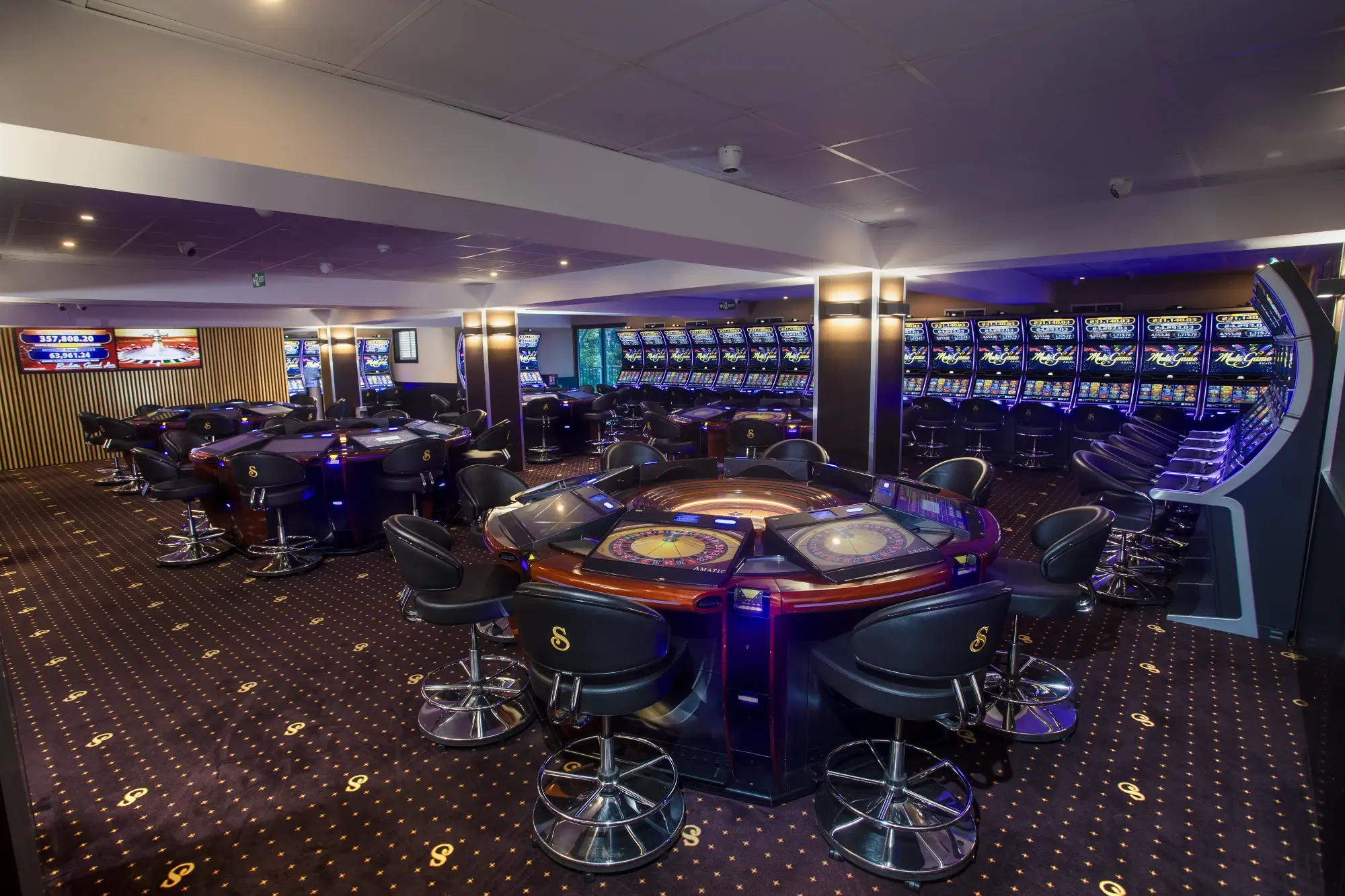 A roulette table at the centre of the room, screens on the left wall and slot machines running the length of the right, Senator Club, Mauritius