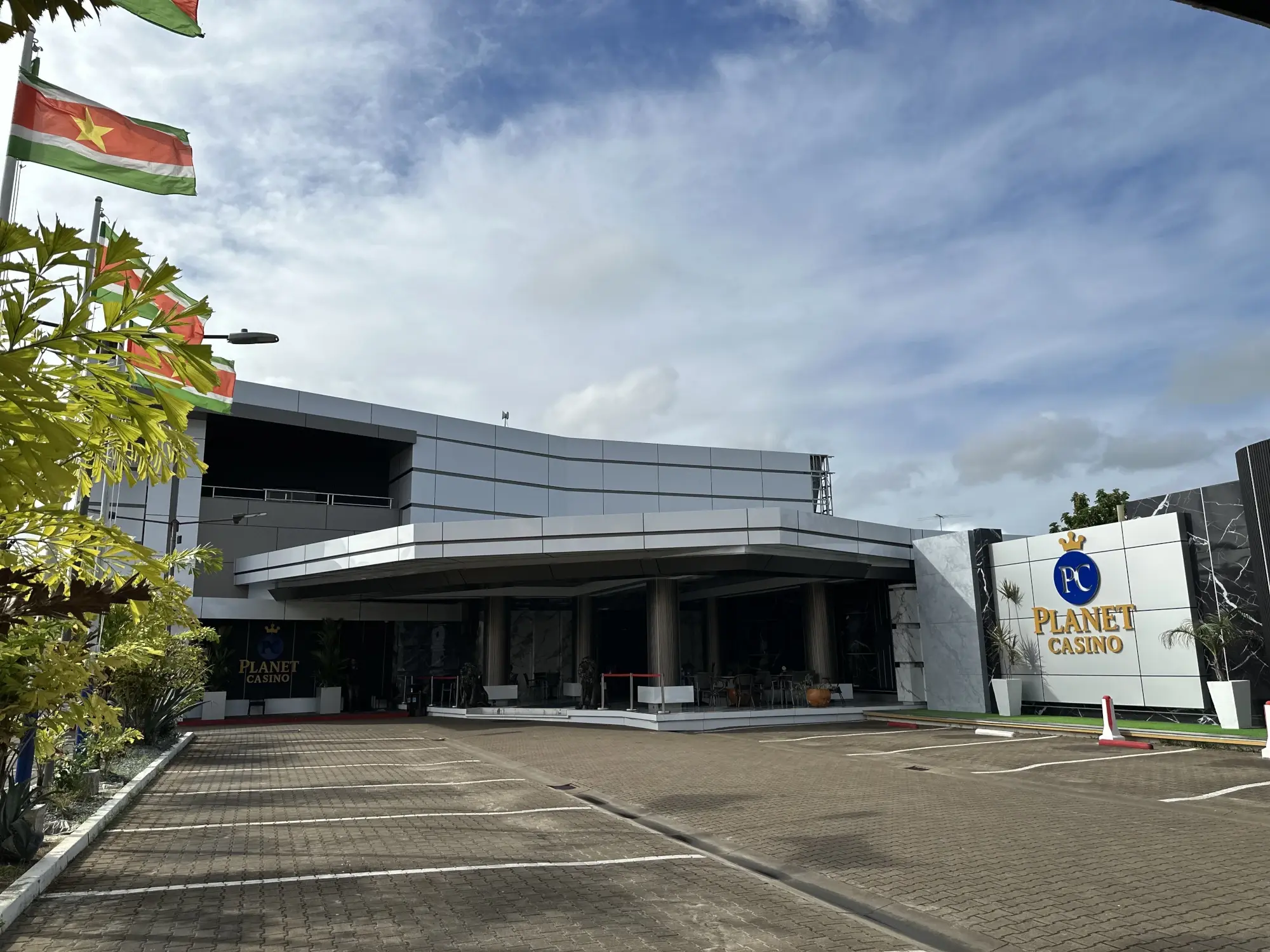 The Planet Casino building seen across its car park in Paramaribo, Suriname flags flying beside the entrance canopy